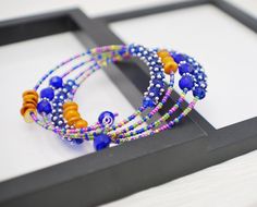 This beaded wrap bracelet is made with four rows of beads strung onto silver plated memory wire. Coordinating glass seed beads are paired with various glass, crystal and shell beads in shades of cobalt blue and golden yellow with accents of silver throughout. Super bold and colorful, this bracelet will be a pretty splash of color to any outfit! Memory wire maintains its shape, no matter how it is twisted or stretched. Instead of using a clasp, you wind it onto your wrist, making it easy to fit a Gray Earrings, Beaded Necklace Diy, Memory Wire Bracelet, Seed Bead Bracelet, Glitter Earrings, Memory Wire Bracelets, Bracelet Blue, Sparkle Earrings, Bracelet Beaded