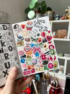 someone holding up a book with lots of stickers on it