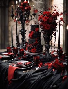 a table topped with black and red cake covered in roses next to tall candelabra filled with candles