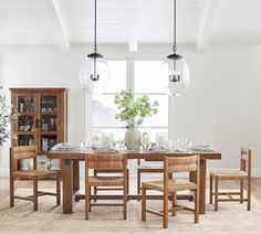 a dining room table and chairs in front of a window with an open bookcase