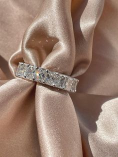 a diamond ring is sitting on top of a satin material with a ribbon around it