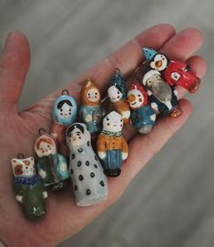 small ceramic figurines in the palm of someone's hand, all dressed up