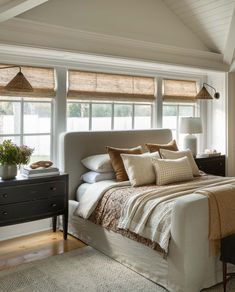 a bed with pillows and blankets in a bedroom next to two lamps on either side of the bed