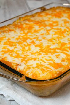 a casserole dish with cheese on it sitting on a white cloth next to a fork