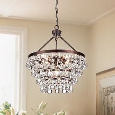 a chandelier hanging from the ceiling in a dining room with flowers on the table