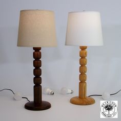 two wooden table lamps sitting next to each other on top of a white countertop