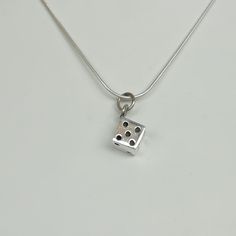 ▪︎ ONE sterling silver dice pendant/charm. ▪︎ This multipurpose piece can be used as a charm for neck chains, bracelet chains, hoops ,key chains etc ▪︎ Size: 8 x 12 mm Weight: 4.7 gm ▪︎ This pendant is handmade with hypoallergenic sterling silver. Most of my pieces are marked with a 925 silver stamp. ▪︎ Please note: This pendant comes WITHOUT the chain, however, you can add a snake chain in the required length while making your selection. You can also opt to choose other kinds of chains and brac Silver Sterling Square Pendant Charm Necklace, Silver Charm Necklace With Square Sterling Pendant, White Gold Charm Necklaces With Box Chain For Gift, White Gold Charm Necklace With Box Chain As Gift, White Gold Box Chain Charm Necklace For Gift, Silver Symbolic Square Pendant Jewelry, Symbolic Silver Square Pendant Jewelry, Sterling Silver Charm Necklace With Engraved Square Pendant, Sterling Silver Jewelry With Box Chain And Square Pendant