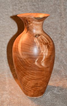 a wooden vase sitting on top of a carpeted floor