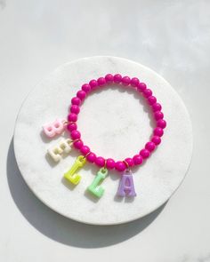 Introducing our delightful Personalised Multicoloured Name Children's Bracelets, a whimsical accessory that will bring joy and style to your little one's wrist!  These charming bracelets are a perfect blend of vibrant colours and playful customisation, making them an ideal bespoke gift for any special occasion. Each bracelet is beautifully adorned with adorable iridescent letter charms that hang and dangle gracefully from delicate gold hoops, adding a touch of elegance to the design. The best pa Personalized Pink Novelty Charm Bracelet, Customizable Pink Charm Bracelet For Birthday, Novelty Bracelets With Letter Beads For Birthday, Novelty Birthday Bracelets With Letter Beads, Novelty Round Beads Bracelet For Birthday, Personalized Pink Novelty Bracelets, Personalized Pink Charm Bracelet, Multicolor Personalized Novelty Charm Bracelet, Playful Pink Beaded Bracelets