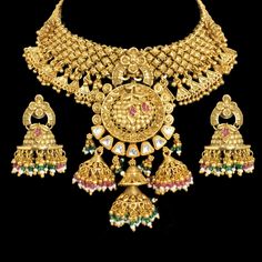 Temple Jewelry Set inspired by Amrapali India's rich heritage. This exquisite piece is a testament to the artistry of temple jewelry, adorned with intricate details and antique finishes. Reflecting the traditions of South India, it combines elegance with timeless charm. Created by Amrapali, a renowned name in jewelry, this necklace features Kundan elements for added opulence. Perfect for special occasions, it celebrates the cultural legacy of India and adds a touch of regal beauty to any ensembl Bollywood Style Ceremonial Jhumkas With Intricate Design, Bollywood Style Jhumkas With Intricate Design For Ceremonial Occasions, 22k Gold Cutdana Jewelry For Puja, 22k Gold Kundan Necklace With Intricate Design For Puja, Heavy Temple Jewelry Set In 22k Gold, Heavy 22k Gold Jewelry For Navratri, Ceremonial Festive Jhumkas With Intricate Design, Heavy 22k Gold Temple Jewelry Set, Traditional Jhumkas With Intricate Design For Ceremonial Use