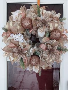 a wreath is hanging on the front door with ribbon around it and flowers in the center