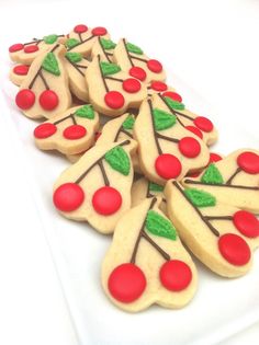 decorated cookies arranged in the shape of trees and cherries on a white platter