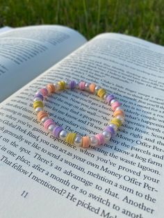 an open book with a colorful beaded bracelet sitting on top of it's pages