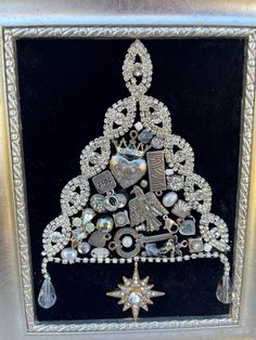 an ornate christmas tree made out of various jewels and other items in a silver frame