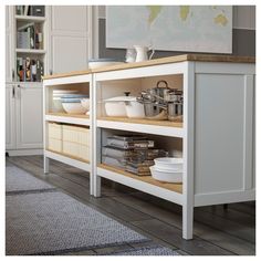 a kitchen with white cupboards and shelves filled with bowls, pans and utensils