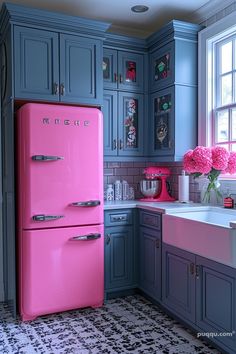 a pink refrigerator in a kitchen with blue cabinets