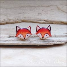 pair of red fox earrings sitting on top of a piece of wood