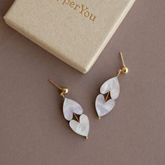 Get ready to wear your heart on your ears with our Love Earrings - a delightful symbol of love and affection! These artistic earrings are designed, laser cut, and lovingly handcrafted right here in the heart of Brighton. We've put extra care into making them lightweight and comfy, so you can wear them with ease all day long. These White Marble Heart Earrings are made with the finest acrylic and FSC certified wood. The nickel-free gold plated earring posts add an extra dash of elegance, making these heart drop earrings the perfect accessory to express your love and pride. With a drop of 4cm, these earrings strike the perfect balance between trendy and chic. They're just what you need to add a touch of love and style to any outfit, whether you're attending a special event or simply spreading Laser Cut Earrings Wood, Colourful Earrings, Artistic Earrings, Laser Cut Wood Earrings, Earrings Wood, Laser Cut Earrings, Love And Pride, Heart Drop Earrings, Earring Posts