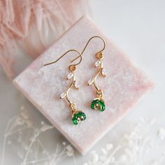 "Emerald Green Flower Earrings // Gold Filled Earrings // Boho Bridal Earrings // Floral Earrings // May Birthstone // Leaf Earrings // Birthday Gift // Bridesmaids Earrings // Four Leaf Clovers  :: Provide an enchanting effect with these lush emerald green floral earring for your woodland wedding :: These emerald green flower earrings are a delicate and feminine design perfect for any boho wedding attire or for adding a little sparkle to your next special occasion. The tiny verdant flower petals are created with faceted glass and are reminiscent to four leaf clovers. These dainty flowers are secured to golden stems featuring small cubic zirconia leaves. The lush green flower earrings are light weight and suspended from comfortable 14k gold filled earrings.  Whether adding these flower ear May Birthstone Crystal Drop Earrings, Flower Shaped May Birthstone Jewelry, Green Flower Earrings For Wedding, Delicate Green Flower Earrings For Gift, Elegant Green Flower Earrings For Gift, Delicate Green Flower Earrings As Gift, Delicate Green Jewelry With Birth Flower, Green Delicate Flower Jewelry, Delicate Green Birth Flower Jewelry