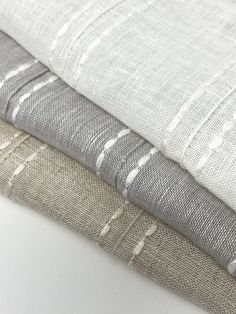 three different types of linens are stacked on top of each other, one is white and the other is grey