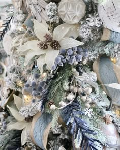 a christmas tree is decorated with silver and white flowers, pine cones, snowflakes and other holiday decorations