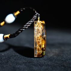 This lovely orgonite pendant features tiger's eye crystals, gold metal flakes, and the shri yantra (male-female balance) symbol cast in clear resin. This powerful amulet will energize, cleanse, and balance the aura field. Orgone is an energy amplifier that can convert negative energy into positive energy. It can effectively increase the energy frequency of the surrounding area, clean the environment and people's vibration frequency, heal wounds, and relieve harmful thinking patterns and pessimis Sri Yantra, Tiger Eye Crystal, Chakra Pendant, Les Chakras, Tiger Eye Stone, Eye Stone, Crystal Necklace Pendant, Tiger's Eye, Crystal Stone