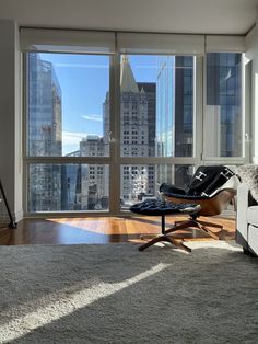 a living room with large windows and a chair in front of the window looking out on the city