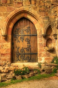 an old stone building with a wooden door and iron work on the front entrance to it