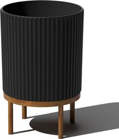 a black planter sitting on top of a wooden stand next to a white wall