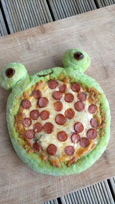 a pizza shaped like a turtle sitting on top of a wooden table covered in cheese and pepperoni