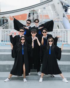 a group of people in graduation gowns posing for a photo on steps with their hands up