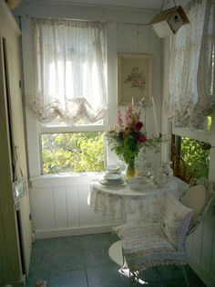 a room with a table, chair and flowers in the vase on the window sill