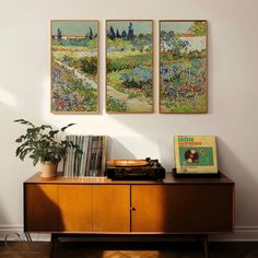 three paintings hang on the wall above a record player