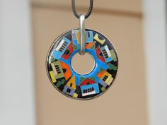 a colorful necklace hanging from a chain with houses and cars painted on the inside circle