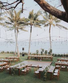 an outdoor venue set up with tables, chairs and greenery on the lawn next to the ocean