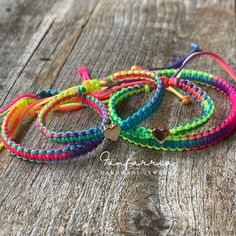 three bracelets with hearts on them sitting on a wooden surface