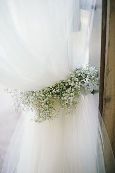 a bouquet of baby's breath sits on the back of a wedding dress