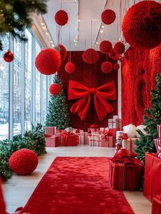 red christmas decorations and presents are on display in this room with large windows, decorated for the holiday season