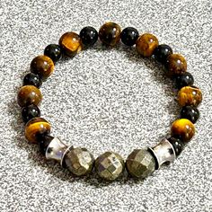 Enhance your style and spiritual well-being with our Men's Gemstone Beaded Bracelet, meticulously handmade with high-quality Tiger Eye, Black Onyx, Faceted Pyritefocal beads, and sleek stainless steel accents.  Made with 8-10 mm beads Fits an 8-8.5" wrist  This BOLDLY unique bracelet is designed for both fashion and function, offering powerful metaphysical benefits and a timeless, masculine look. Key Features: *Gemstones Used: Tiger Eye, Black Onyx, Faceted Pyrite *Accents: Stainless Steel *Hand Bohemian Black Bracelets With Polished Beads, Black Bohemian Bracelet With Polished Beads, Bohemian Black Bracelet With Polished Beads, Spiritual Beaded Obsidian Bracelets, Bohemian Black Stretch Bracelet With Gemstone Beads, Artisan Black Bracelet For Gift, Onyx Beaded Bracelets For Meditation, Obsidian Round Beads Bracelets For Meditation, Spiritual Onyx Beaded Bracelet With Black Beads