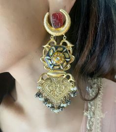 Discover our gold-plated, long earrings with intricate carved design, featuring vibrant red carved stones and stunning blue meenakari. Perfect for adding a touch of elegance to any outfit. Ornate Gold Danglers With Meenakari, Traditional Chandbali Jhumkas For Designer Wear, Traditional Gold Plated Danglers For Diwali, Bollywood Style Designer Earrings With Cutdana, Bollywood Cutdana Earrings For Designer Wear, Bollywood Designer Cutdana Earrings, Traditional Kundan Filigree Earrings, Gold Plated Meenakari Temple Jewelry Danglers, Traditional Gold Plated Danglers For Festive Occasions