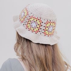 a woman wearing a white crocheted hat with flowers on the brim and sides