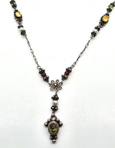 Boho multi Gemstone Garnet citrine peridot tribal sterling silver vintage necklace. Good used condition with little to no signs of normal wear. Great patina present. Stamped 925 on the back of the pendant and the clasp. Unique decorated S clasp has a citrine cab in the center. Each bead is faceted gemstone which include: peridot, citrine, garnet and white pearl. Acid tests positive for sterling silver. Gemstones tested with Presidium II gemstone tester. Necklace measures 18 inches long. Pendant measures a 1 and 1/2 inch drop and 3/8ths of an inch wide. Antique Multi-stone Pendant Necklace, Antique Silver Jewelry With Natural Stones, Antique Amber Necklace With Gemstone, Antique Amber Gemstone Necklace, Bohemian Sterling Silver Gemstone Necklaces, Bohemian Sterling Silver Gemstone Necklace, Vintage Citrine Gemstone Jewelry, Silver Long Necklace With Stones, Vintage Pendant Jewelry With Stones