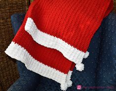 a red and white knitted blanket sitting on top of a blue chair next to a pillow