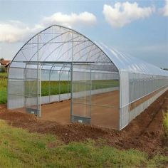 a large greenhouse in the middle of a field with lots of dirt on the ground