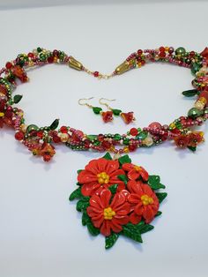 "Everyone could use a little Joy and a little Luck these days. This oriental-inspired statement necklace is predominantly red, which means joy, luck, and happiness in Chinese culture. Yellow, green, and cream colors complete the look. The floral pendant is polymer clay (made by me), coated with gloss polyurethane. The multiple strands have flower and leaf  clusters and handmade flowers, as well as a variety of glass and ceramic beads, joined together with gold-plated cones. The clasp is a handmade hook-and-eye. The matching flower earrings are 1 7/8\" long. The clasp wire and earwires are gold-plated and nickel-free. Bring some Joy and Luck into your life today!" Red Flower Polymer Clay Jewelry, Red Flower-shaped Polymer Clay Jewelry, Red Polymer Clay Jewelry For Gift, Red Polymer Clay Jewelry For Gifts, Red Polymer Clay Necklace For Gift, Red Hand Painted Pendant Necklaces, Traditional Red Hand Painted Necklace, Traditional Red Hand-painted Necklace, Unique Red Polymer Clay Necklace