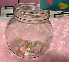 a glass jar filled with lots of candy on top of a pink carpeted floor