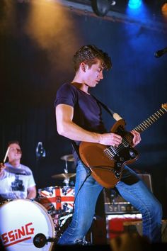 a young man playing an electric guitar on stage