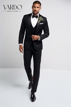 a man in a tuxedo is posing for the camera with his hand on his hip