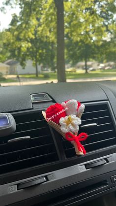 a car dashboard with a red and white flower in the air vent on top of it