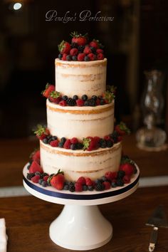 a three tiered cake with berries and strawberries on top